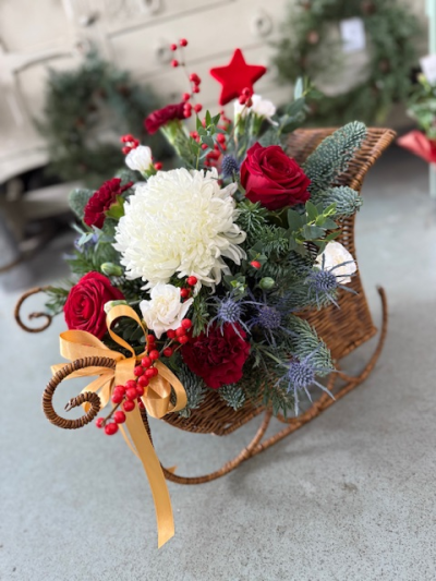 Sleigh Bells - A festive arrangement displayed in a large wicker sleigh, filled with fresh winter blooms. Perfect for a gift, a table centre or remembering a loved one.